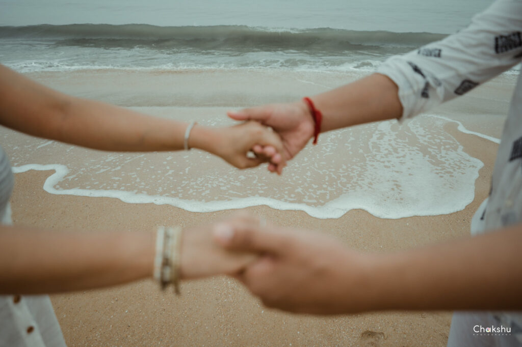 A couple holding hands on the beach, capturing a romantic moment, perfect for a pre-wedding photographer in Delhi.