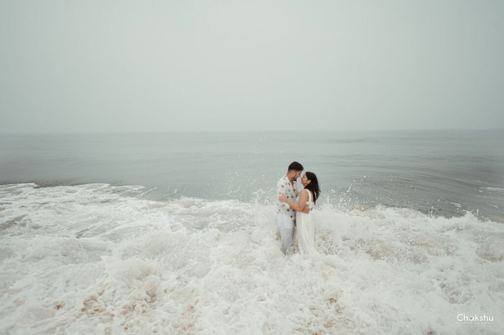 A couple enjoys the ocean at the beach, symbolizing love and joy, as seen through the lens of a pre-wedding photographer in Delhi.