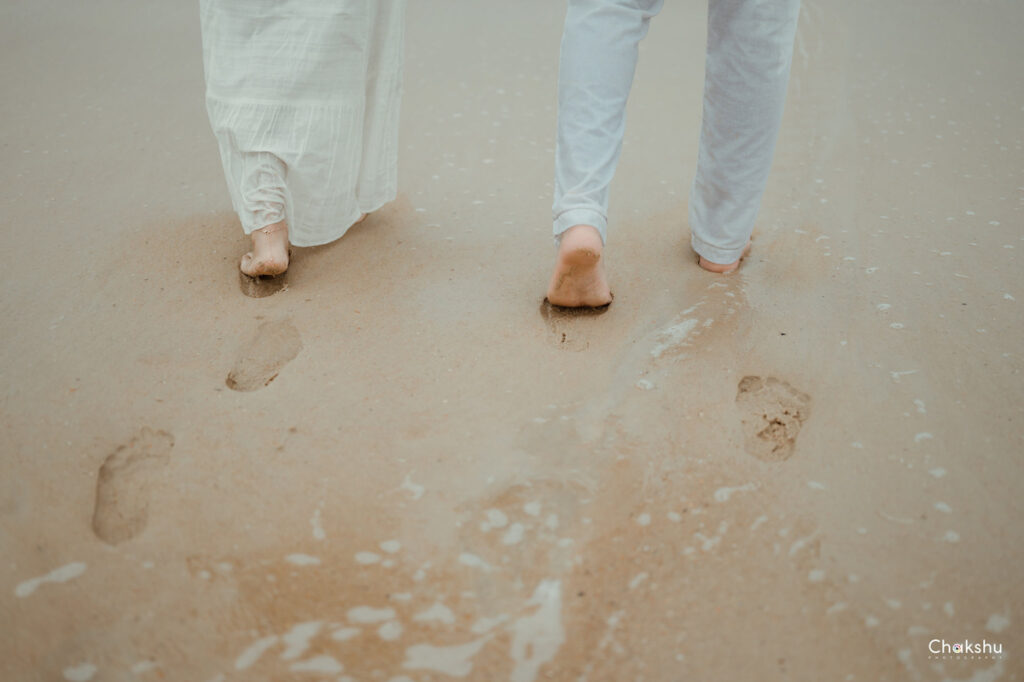 A couple strolls along the beach, leaving footprints in the sand, captured by a pre-wedding photographer in Delhi.