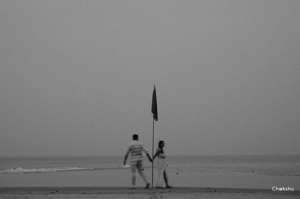 A couple enjoys a beach walk, holding hands, creating a picturesque scene for a pre-wedding photographer in Delhi.