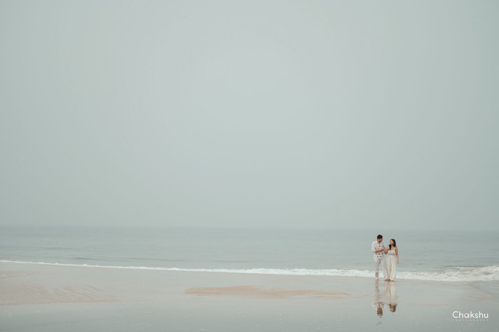 A couple enjoys the ocean at the beach, symbolizing love and joy, as seen through the lens of a pre-wedding photographer in Delhi.