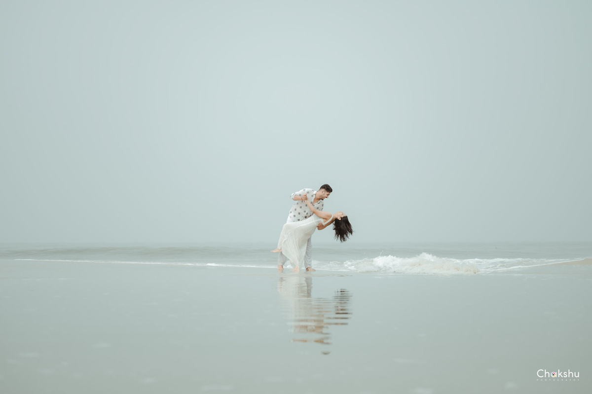 A couple stands in the ocean at the beach, capturing a romantic moment, showcasing the work of a pre-wedding photographer in Delhi