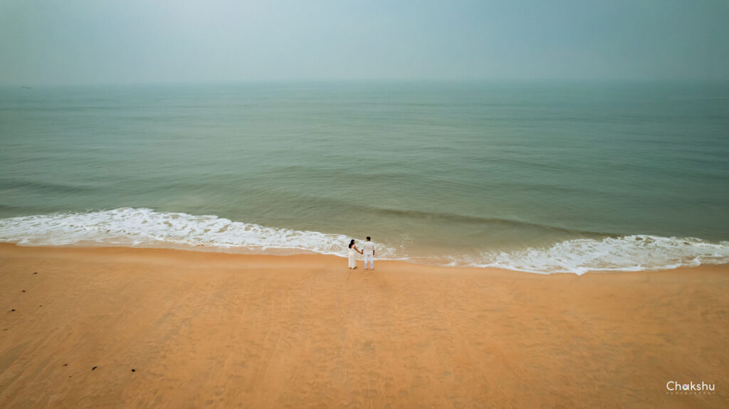 A person strolls along the beach, waves lapping at their feet, captured by a pre-wedding photographer in Delhi.