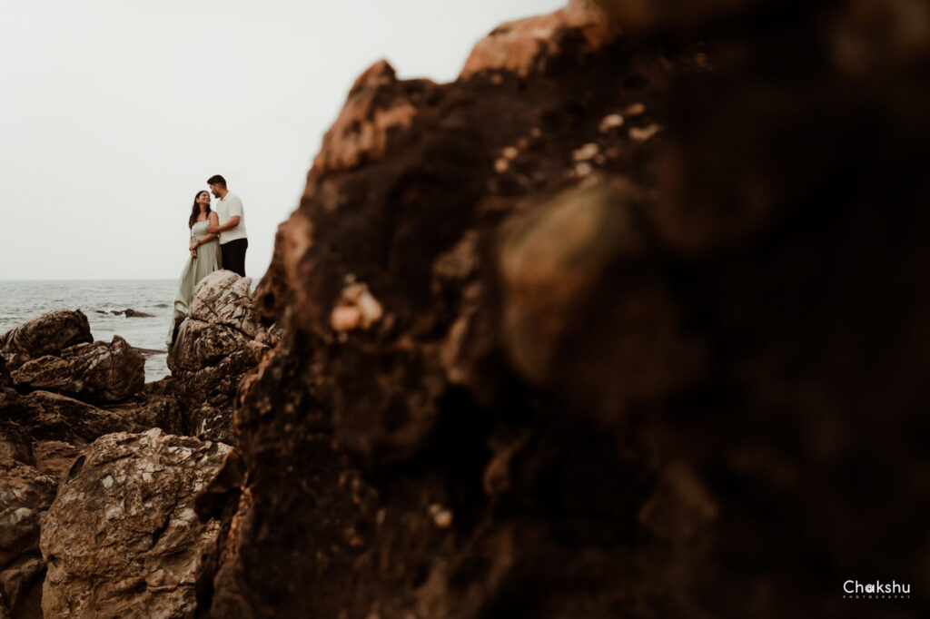 A couple standing behind a big rock image captured by best pre-wedding photographer in delhi.