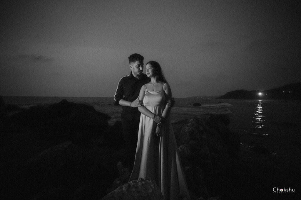 Beautiful pre wedding image of a cute couple black & white image standing near a beach on some rocks image captured by best pre- weeding photographer in delhi.